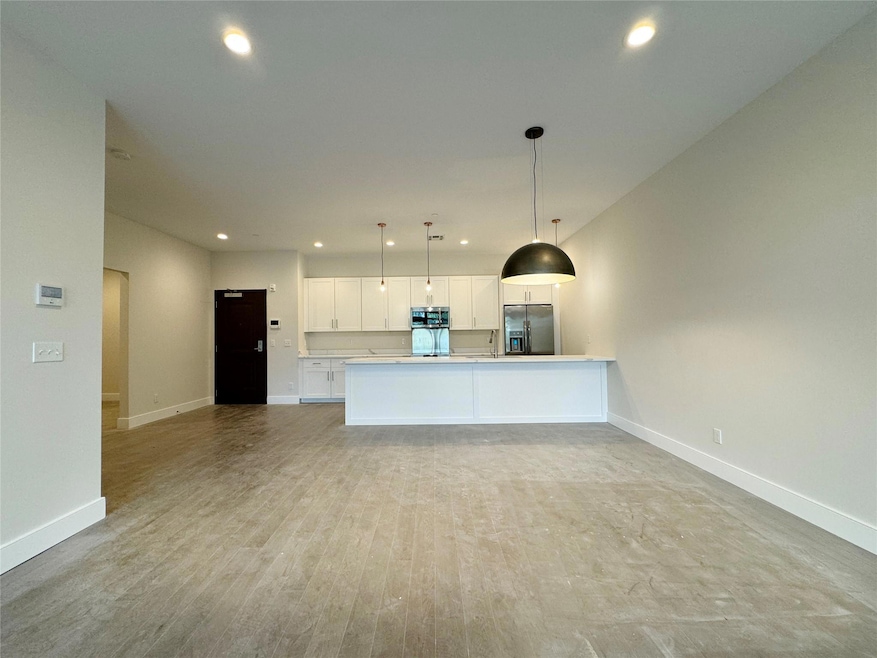 Kitchen featuring stainless steel appliances, open floor plan, white cabinetry, recessed lighting, and decorative light fixtures