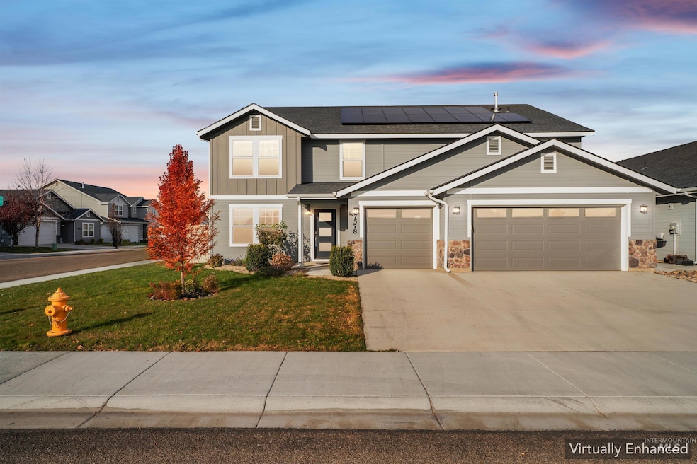 View of front of property featuring concrete driveway, solar panels, board and batten siding, a front lawn, and an attached garage