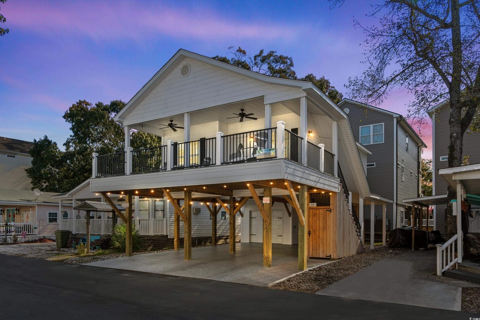 View of front of house featuring ceiling fan, a balcony, and a carport