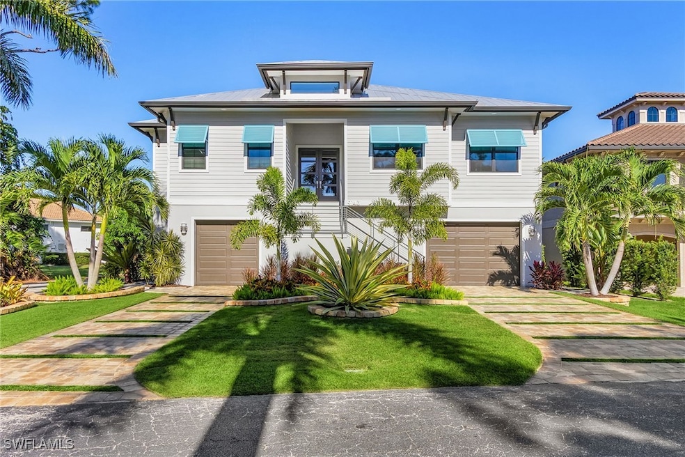 Coastal home featuring a front lawn, driveway, and an attached garage