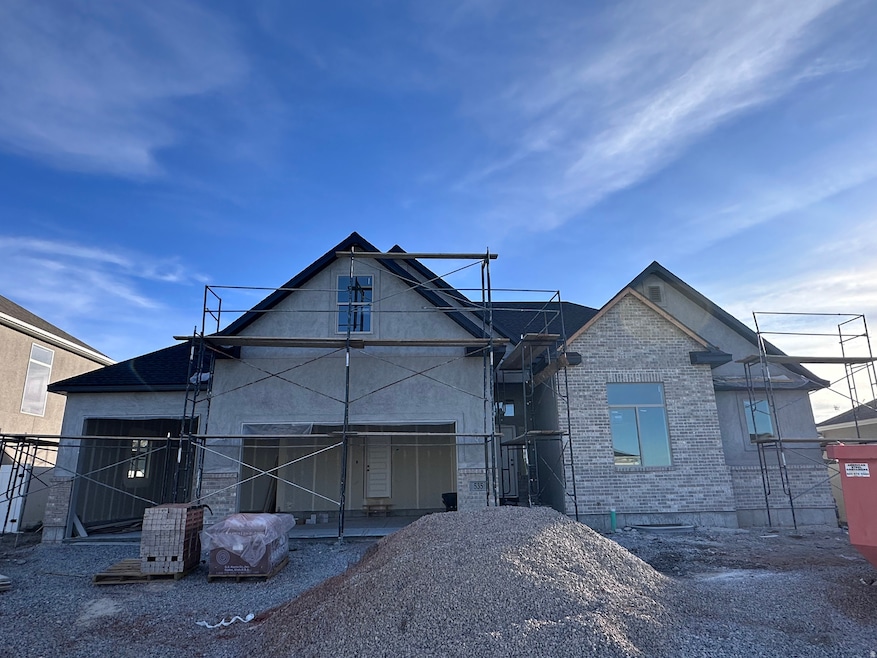View of front of home featuring a patio, brick siding, and stucco siding