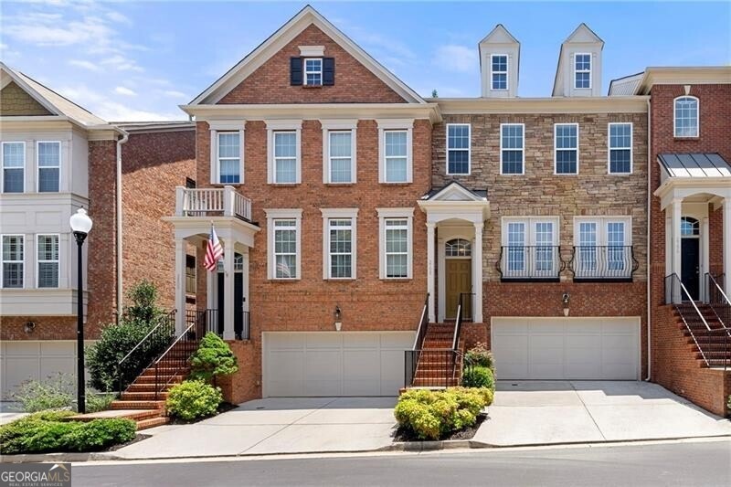 Multi unit property featuring stairs, driveway, an attached garage, and brick siding