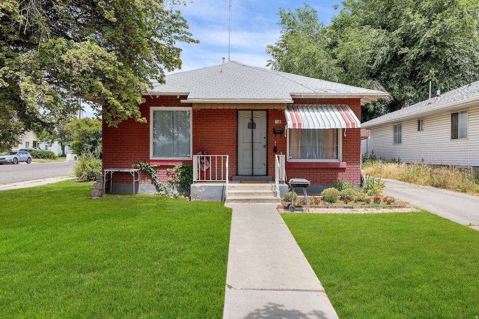 Bungalow-style home with a front lawn, brick siding, and roof with shingles