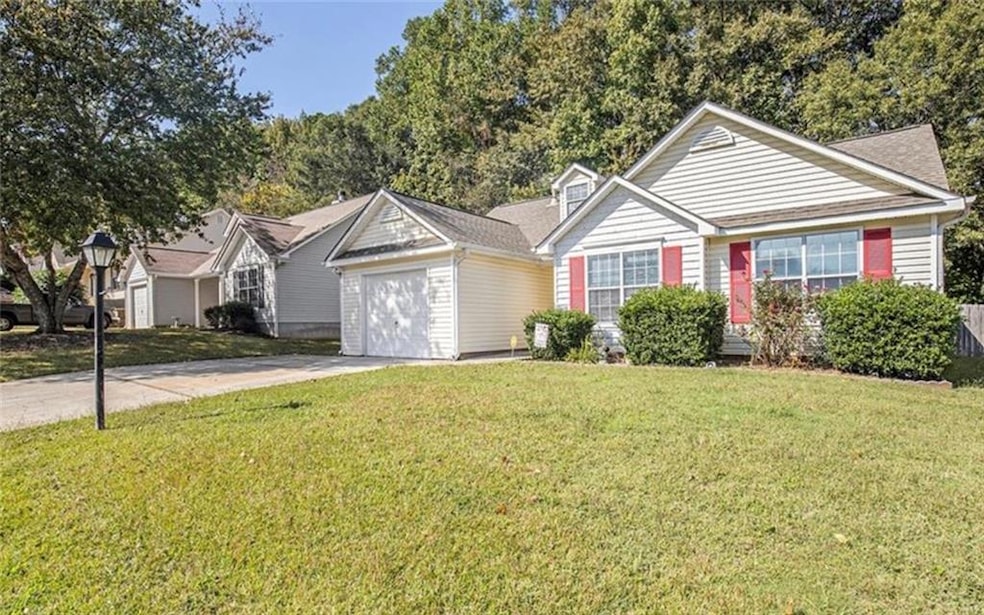 Single story home with concrete driveway, a front lawn, and a garage