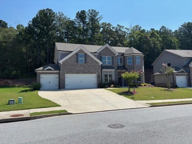 View of front of house with concrete driveway, a front lawn, and a garage