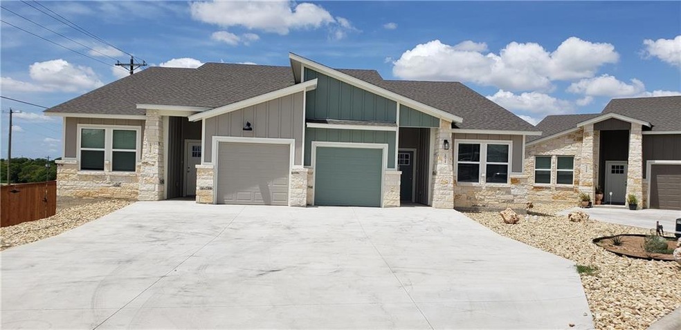 View of front facade featuring stone siding, a garage, driveway, and roof with shingles
