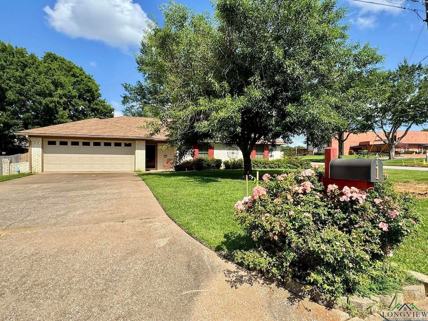 View of front facade featuring driveway, brick siding, a front yard, and a garage