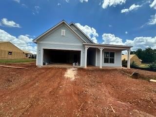View of front of property featuring driveway, an attached garage, and a porch