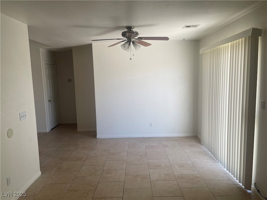 Spare room featuring ceiling fan and light tile pa
