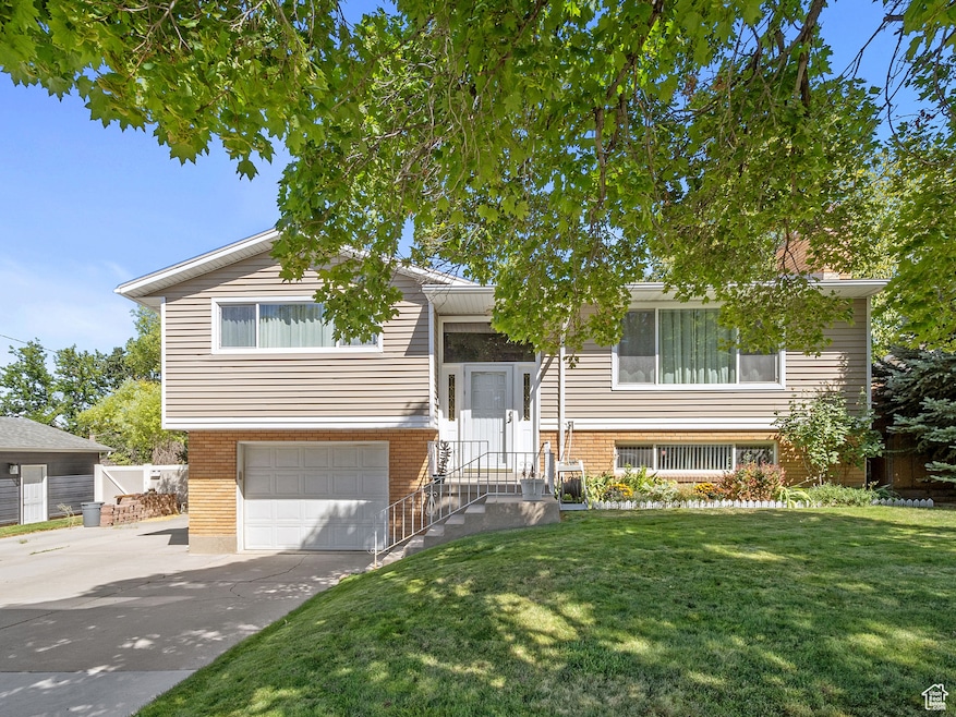 Split foyer home featuring brick siding, concrete driveway, a front yard, and an attached garage