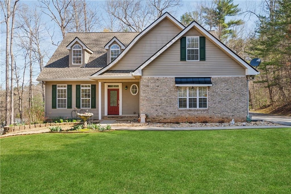 View of front facade with a front lawn, a shingled