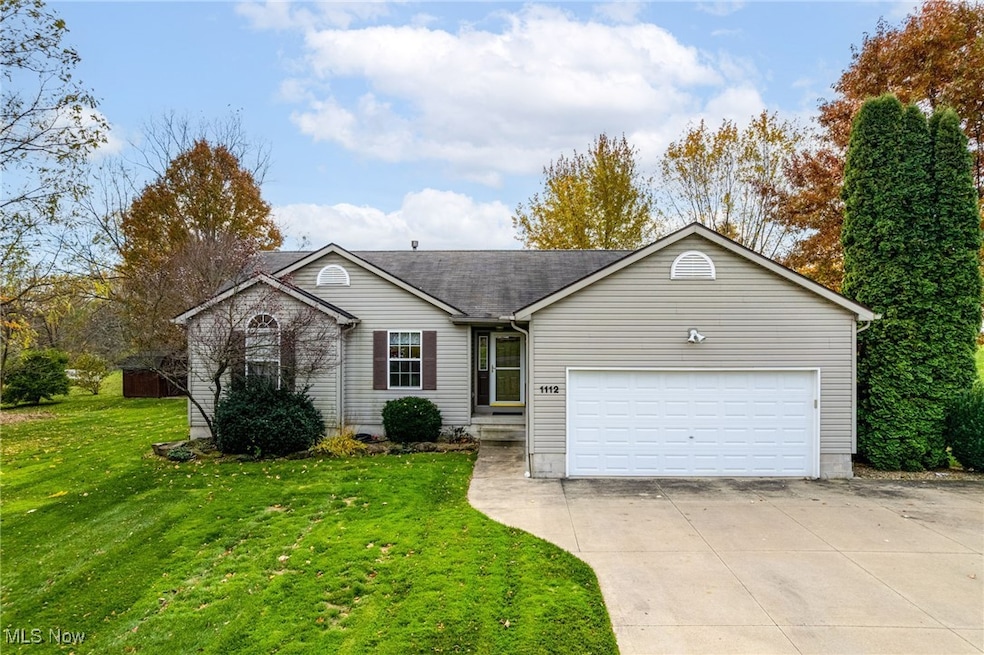 Single story home featuring concrete driveway, a front yard, an attached garage, and a shingled roof