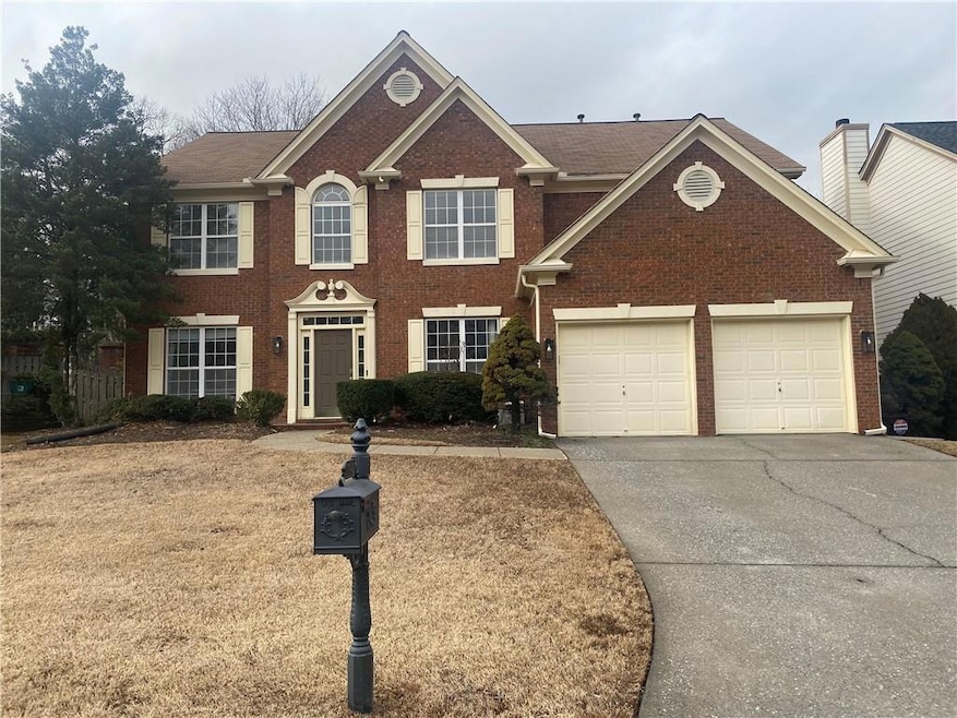 Colonial house with driveway, an attached garage, and brick siding