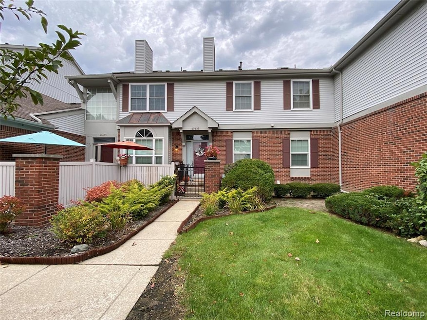 View of front of home with a chimney, a gate, and brick siding