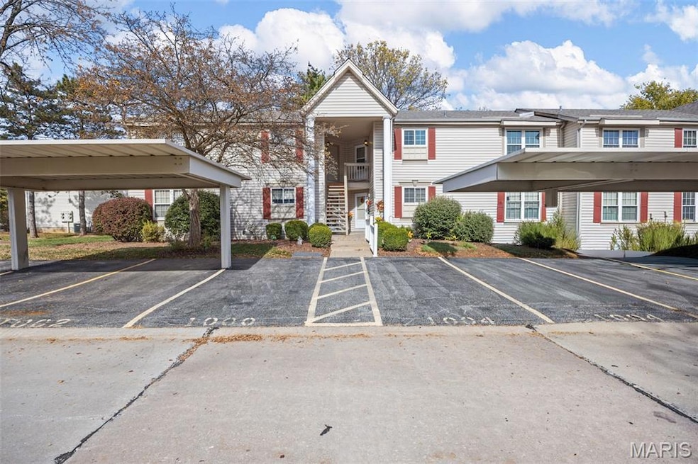 View of building exterior featuring covered and uncovered parking