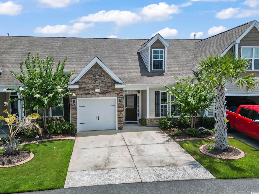View of front of property featuring stone siding, a shingled roof, driveway, and an attached garage