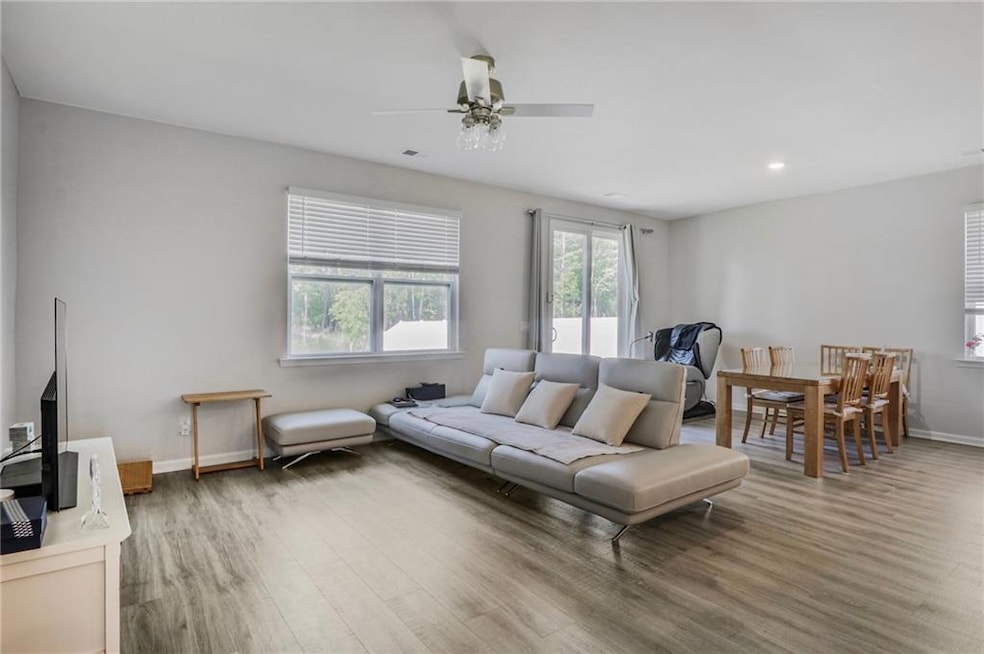 Living room featuring baseboards, a ceiling fan, wood finished floors, and recessed lighting