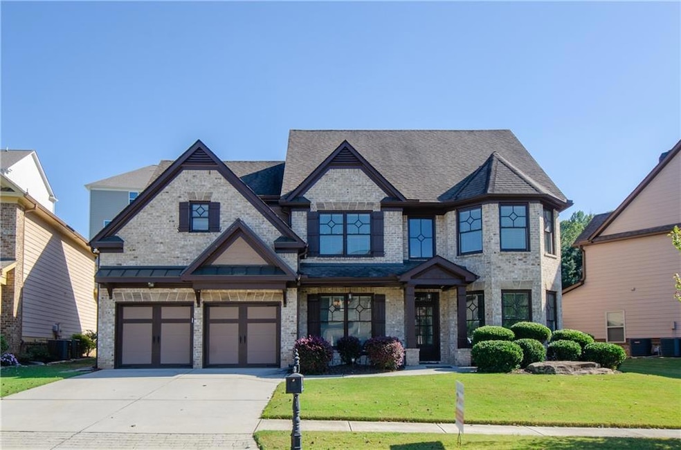 View of front of home with a front lawn, concrete driveway, brick siding, and a garage