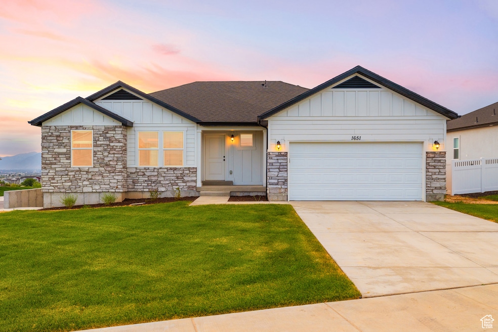 View of front of property featuring stone siding, board and batten siding, an attached garage, and concrete driveway