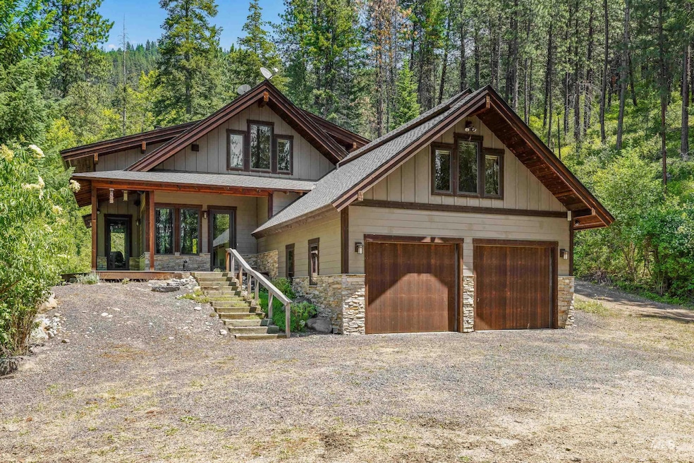 View of front of home with stone siding, a wooded view, and attached garage