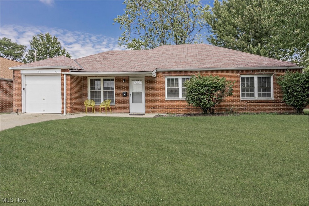 Ranch-style home featuring roof with shingles, a front yard, a garage, brick siding, and concrete driveway