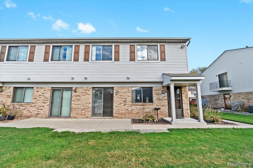 Back of house featuring a lawn and brick siding