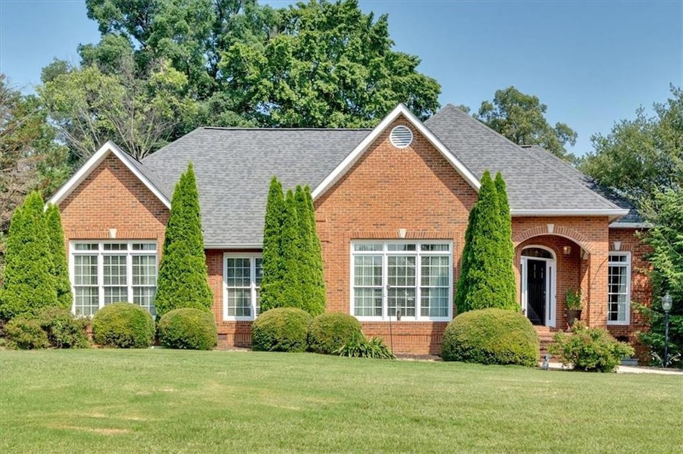 View of front of property featuring a front lawn, brick siding, and roof with shingles