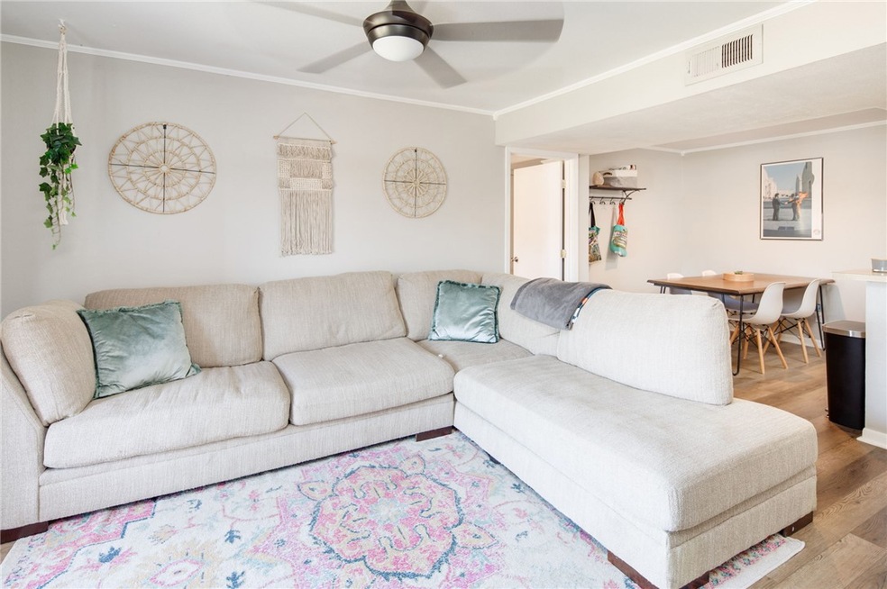 Living area with ceiling fan, visible vents, wood