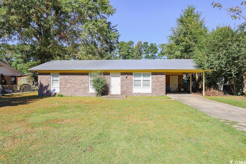 Ranch-style house featuring a front yard, an attached carport, concrete driveway, and brick siding