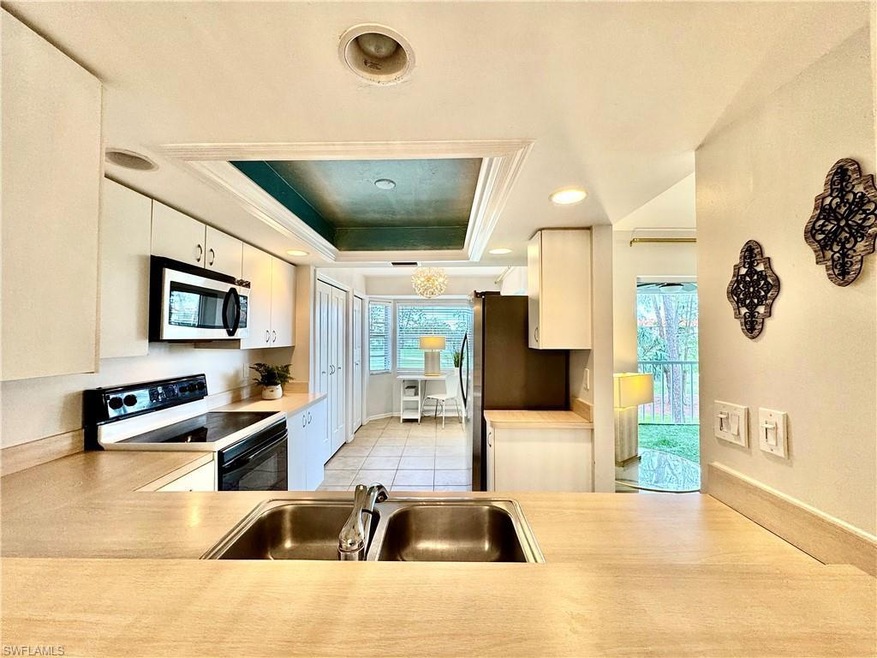 Kitchen with sink, a raised ceiling, white cabinet