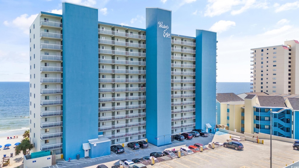 View of apartment building / complex with uncovered parking and a water view