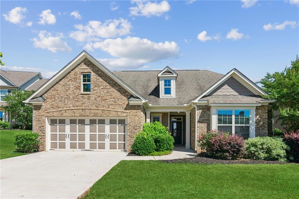 View of front of property with brick siding, a front lawn, driveway, a shingled roof, and a garage