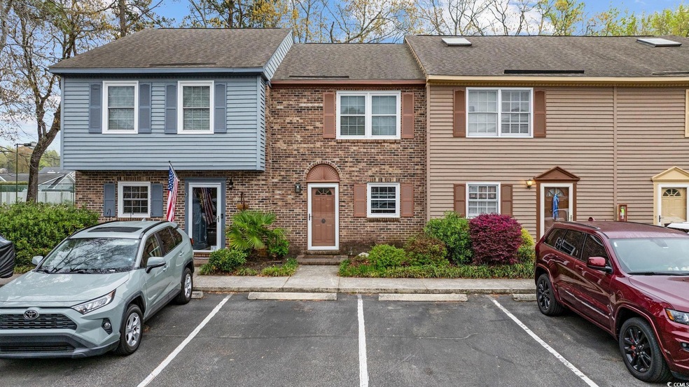 Multi unit property with brick siding, uncovered parking, and roof with shingles
