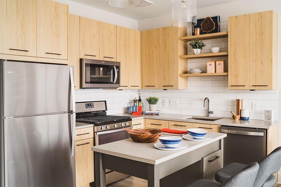 Kitchen with appliances with stainless steel finishes, light brown cabinets, sink, and backsplash
