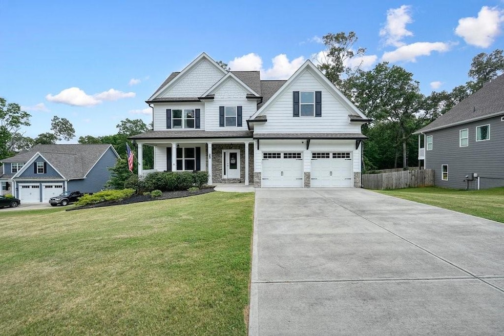 Craftsman-style home with concrete driveway, an attached garage, a porch, stone siding, and roof with shingles