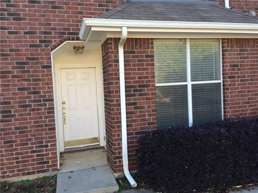 Property entrance featuring brick siding and a shingled roof