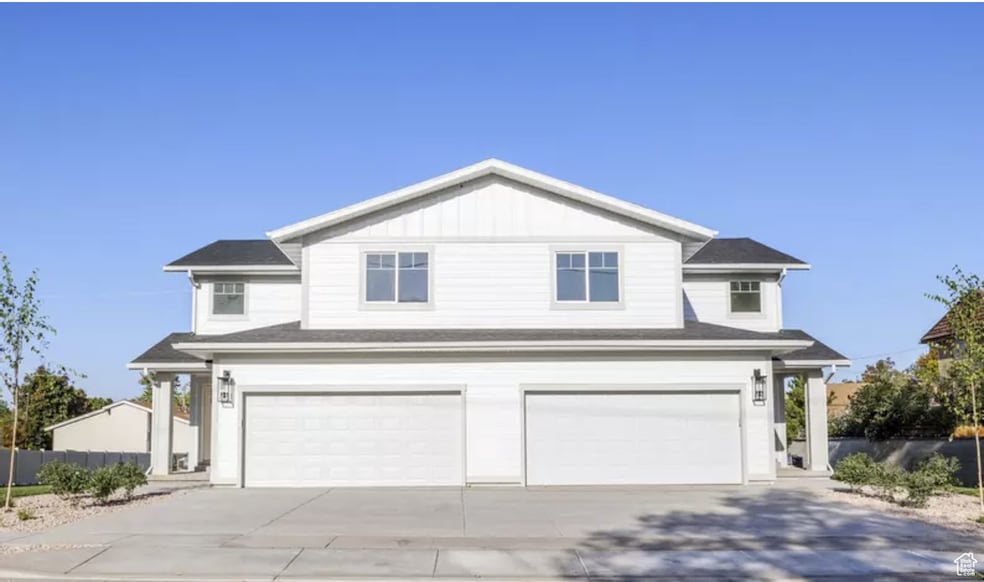 View of front facade with board and batten siding, a garage, and driveway