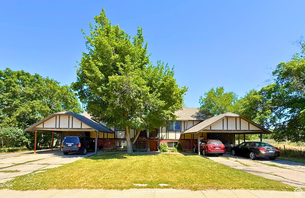 View of front facade with driveway, a detached carport, a front yard, and stairway