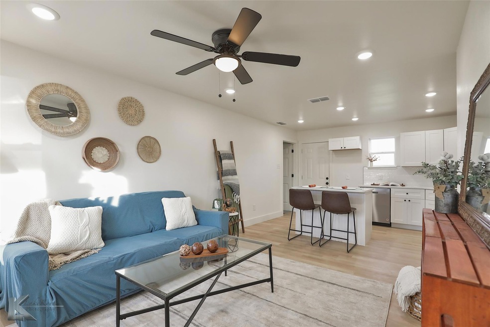 Living room with ceiling fan and light wood-type f