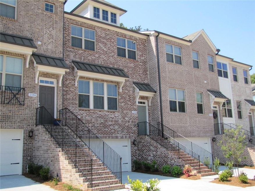 Townhome / multi-family property featuring an attached garage, brick siding, a standing seam roof, and driveway