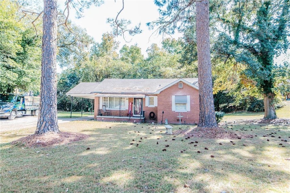 Ranch-style home with a porch, a carport, brick siding, and a front yard