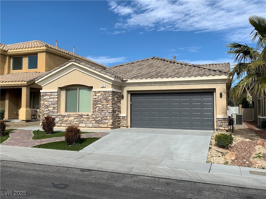 View of front of property featuring stone siding, driveway, stucco siding, an attached garage, and a tiled roof
