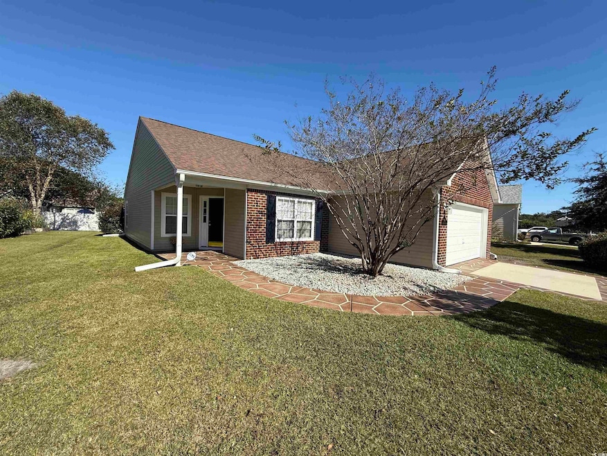 Ranch-style house with a front yard, driveway, a shingled roof, a garage, and brick siding