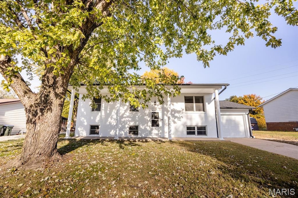 Bi-level home featuring a front lawn, a garage, and concrete driveway