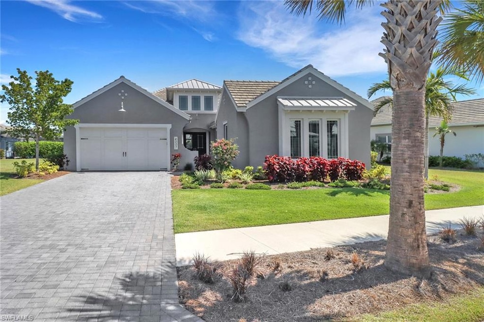 View of front facade with stucco siding, an attached garage, a front lawn, and decorative driveway