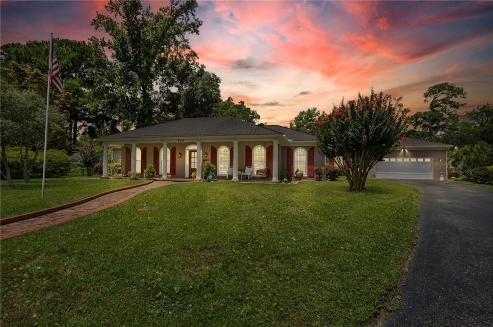 View of front of house with a porch, driveway, a yard, and a garage