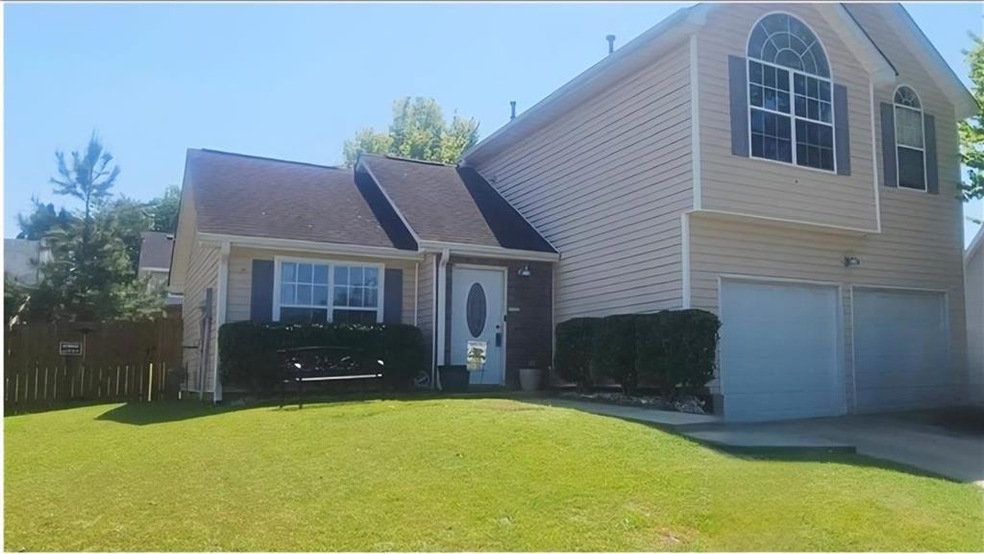 View of front facade with a garage, a front yard, driveway, and a shingled roof