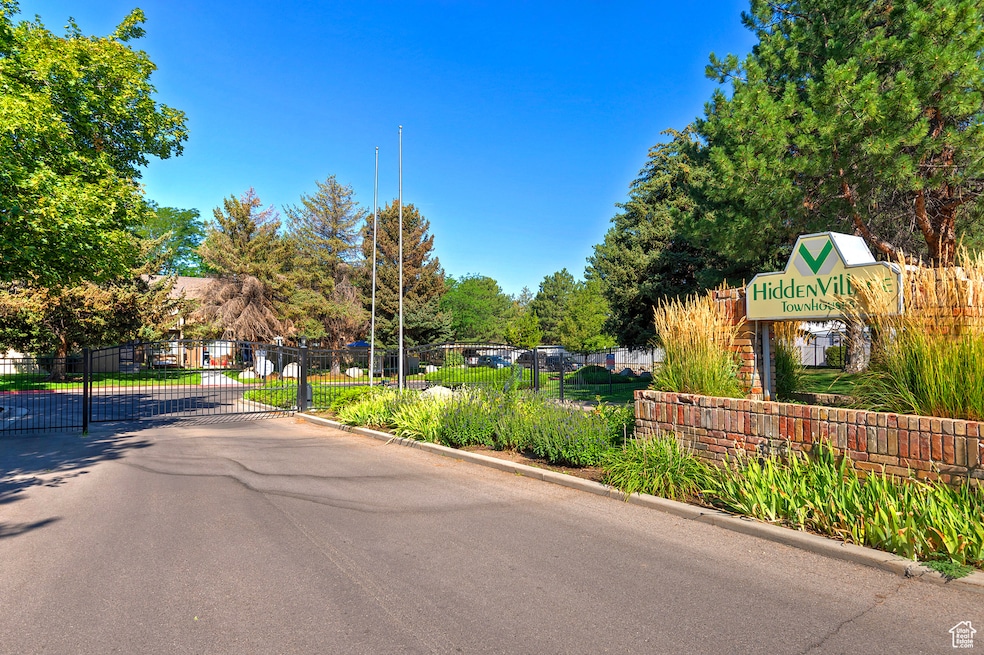 View of asphalt street featuring curbs, a gated entry, and a gate