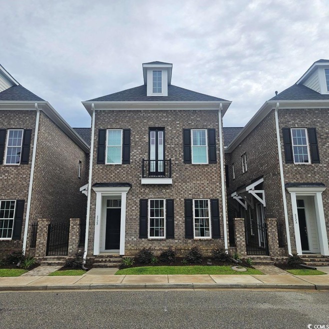 View of front of house featuring brick siding and a balcony