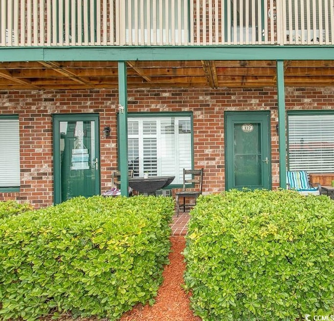 Doorway to property with brick siding and a balcony